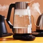 غلاية مياه كهربائية حديثة على منضدة مطبخ، مع بخار يتصاعد منها، ترمز لتوفير الطاقة.