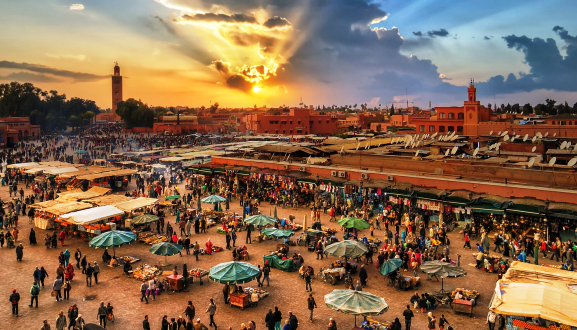 منظر بانورامي لساحة جامع الفنا في مراكش مع مسجد الكتبية في الخلفية، يظهر حيوية المدينة وتراثها.