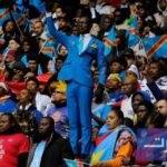 المشجع الكونغولي ميشيل نكوكا مبولادينغا يقف بثبات في المدرجات خلال كأس أمم إفريقيا بالمغرب، مقلداً تمثال باتريس لومومبا.