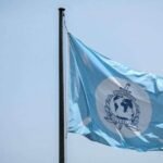 صورة لشعار الإنتربول مع خريطة العالم خلفه، ترمز للتعاون الدولي في مكافحة الجريمة المنظمة وتهريب البشر.