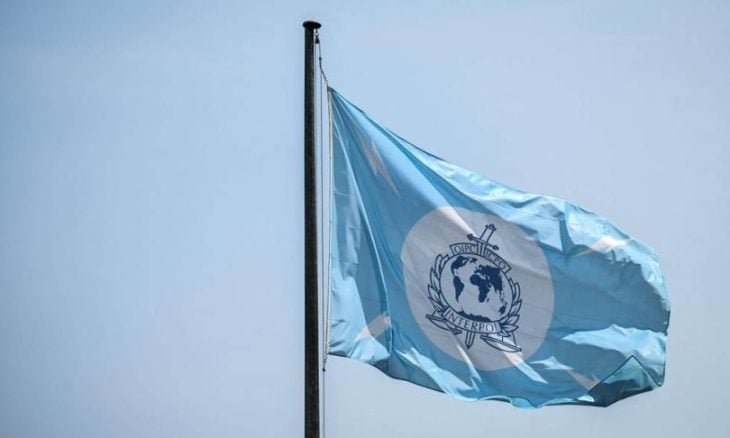 صورة لشعار الإنتربول مع خريطة العالم خلفه، ترمز للتعاون الدولي في مكافحة الجريمة المنظمة وتهريب البشر.