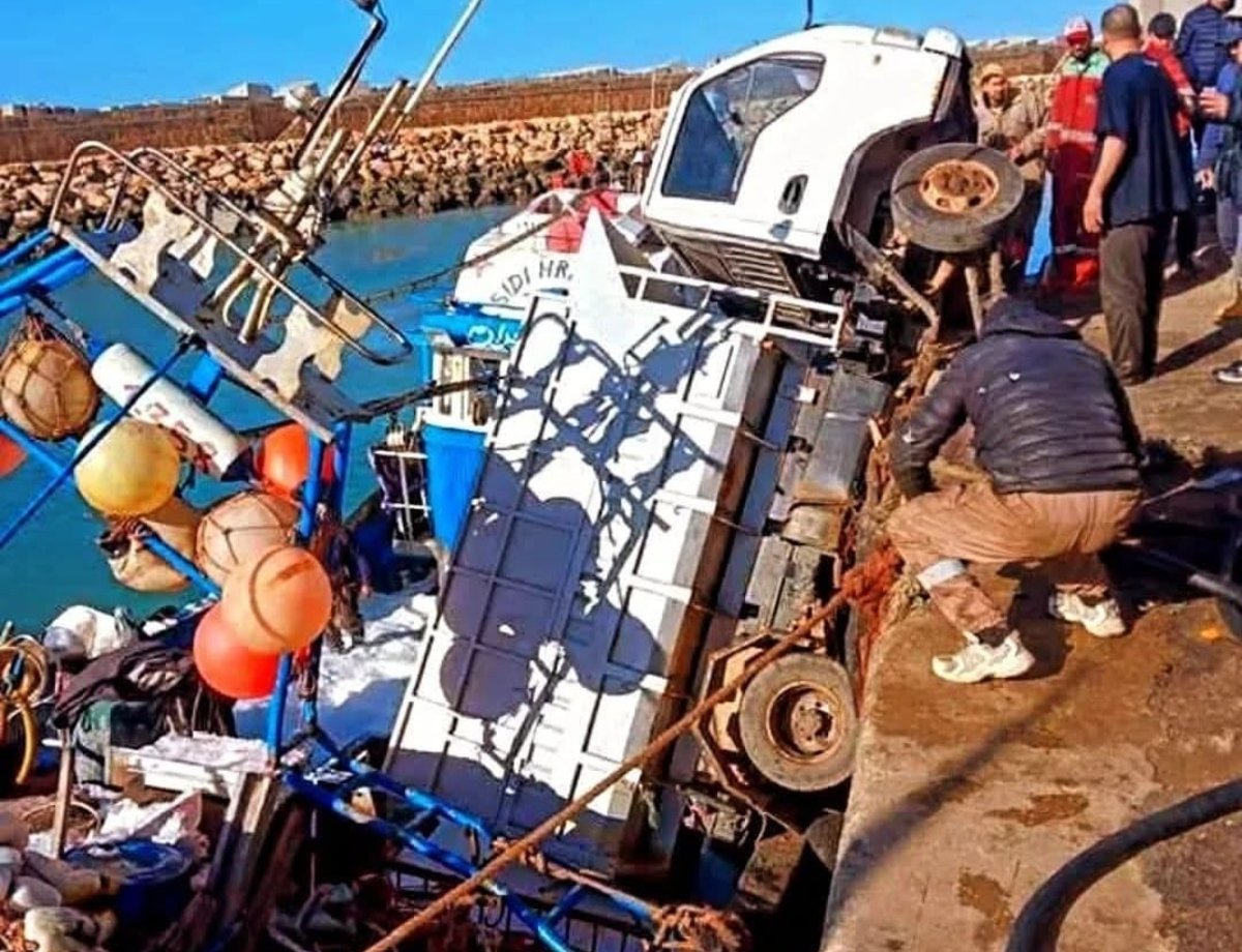 شاحنة بيضاء تستقر فوق مركب صيد أزرق داخل حوض ميناء آسفي بعد حادث غريب.