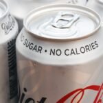 A glass of diet soda next to a glass of water, symbolizing a choice for individuals with type 2 diabetes.