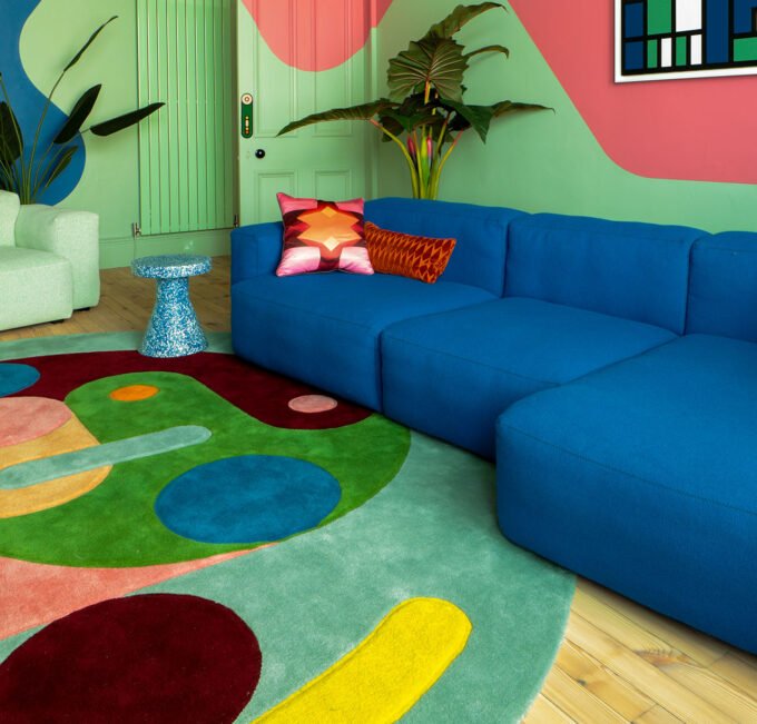 A close-up of a DiscoRectangle rug, showcasing vibrant overlapping geometric shapes in yellow, pink, mint, and burgundy, made from Himalayan wool.