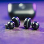 Les écouteurs Motorola Buds Loop noirs, avec leur design à clip d'oreille, posés sur une surface claire, illustrant leur forme ergonomique et compacte.