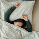 A person holding the eXciteOSA device, a medical-grade silicone mouthpiece connected to an electro-stimulation pulse generator, against a blurred background.