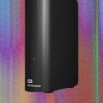 A collection of external hard drives and SSDs on a desk, connected to a laptop