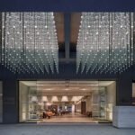 Prague's Brutalist Masterpiece Reimagined: The Fairmont Golden's Artistic Renaissance 8 Exterior view of the Fairmont Golden Prague, showcasing its iconic Brutalist facade and modern transparent annex leading to the Vltava river.