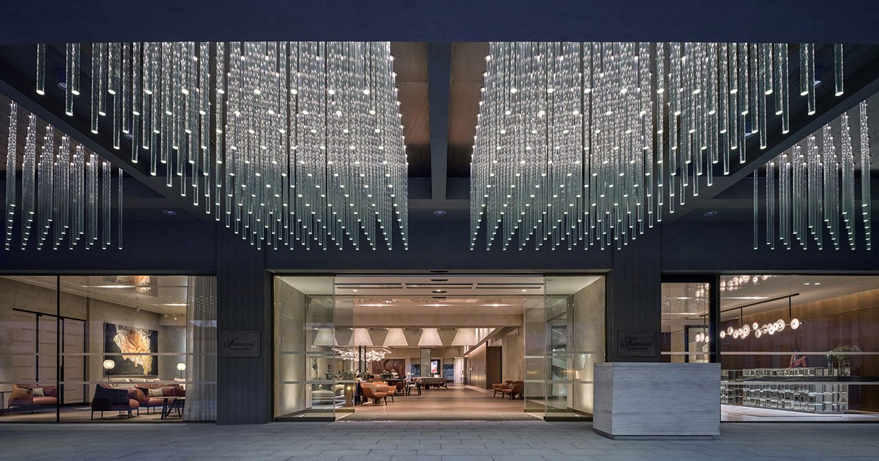 Exterior view of the Fairmont Golden Prague, showcasing its iconic Brutalist facade and modern transparent annex leading to the Vltava river.