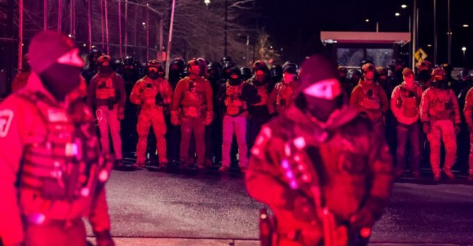 Federal officers face demonstrators protesting outside the Whipple Federal Building in Minneapolis, January 2026, following the fatal shooting of Renee Good.