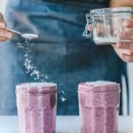 A vibrant purple wild blueberry and oat smoothie in a glass, garnished with granola and honey, ready to be enjoyed.