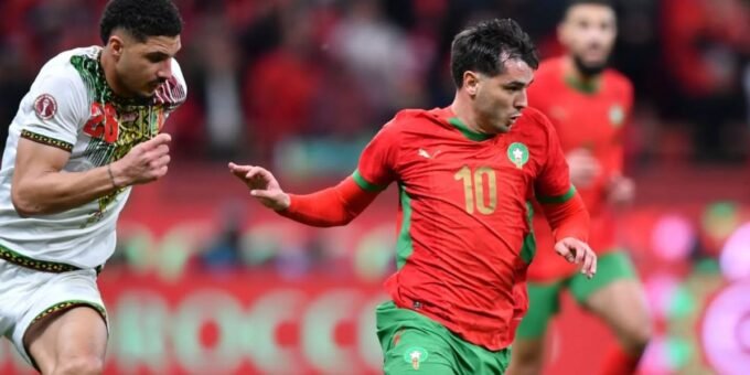 L'arbitre Jean Jacques Ngambo Ndala en action sur un terrain de football, symbolisant l'équité de la finale de la CAN 2025 entre le Maroc et le Sénégal.