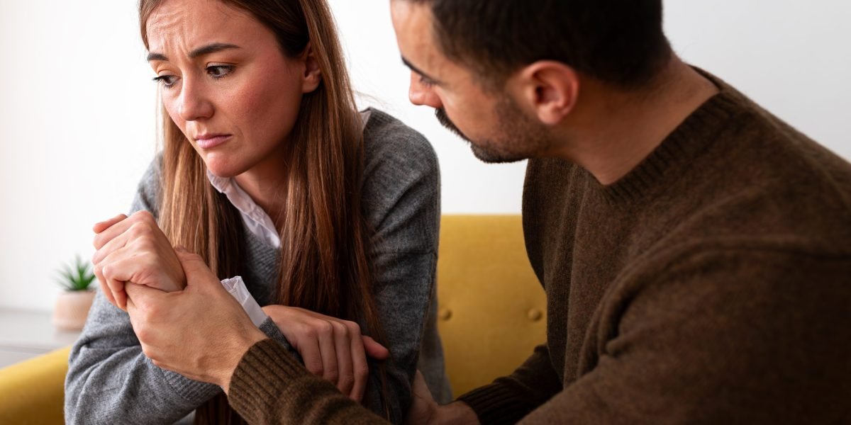 A couple looking at a future vision board with money symbols, but one partner has a deceptive expression.
