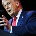 An aerial view of Greenland's icy landscape with a small settlement, symbolizing the challenges of Arctic development and mineral extraction.