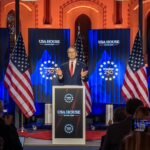 US Treasury Secretary Scott Bessent speaking at the World Economic Forum, with a map of Greenland in the background.