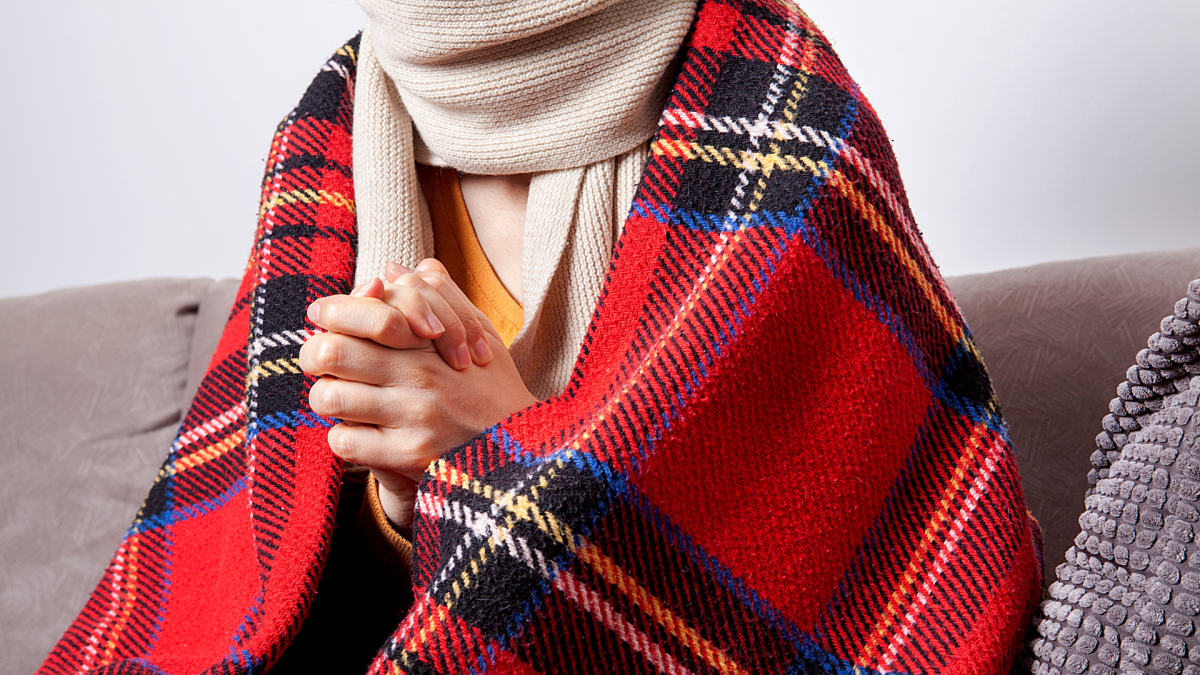 A cozy, warm room during a power outage, with blankets, candles, and a family gathered together.