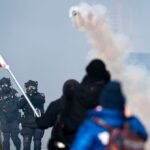 Minnesota's Federalism Bind: Why State Officials Can't Halt ICE's Controversial Operations 6 Federal immigration agents in tactical gear patrolling a street in Minneapolis, with local law enforcement visible in the background, symbolizing the tension between state and federal authority.