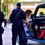 Moroccan police apprehending a suspect, with Interpol logo in the background, symbolizing international cooperation against drug trafficking.