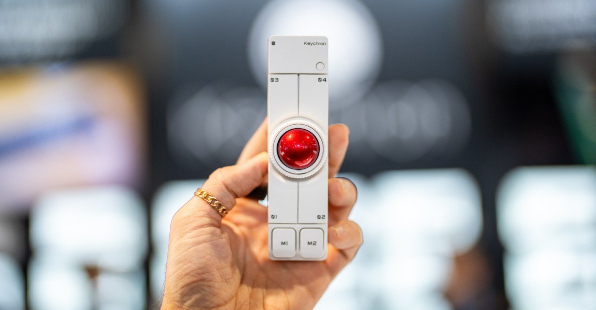 A Keychron Nape Pro trackball positioned in front of a mechanical keyboard, showcasing its compact design.