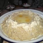 Famille amazighe célébrant Yennayer avec des sfenj et toghrifin, symboles du Nouvel An agraire.