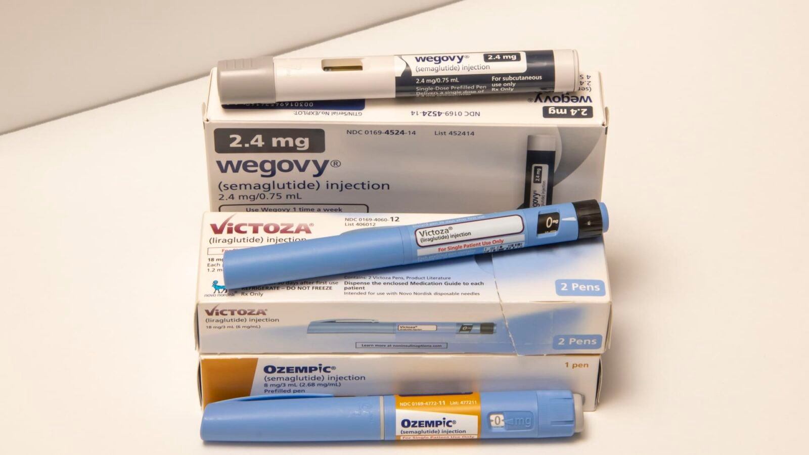 Still life image of Ozempic, Victoza, and Wegovy injectable prescription weight loss medicines.