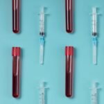 A person's hand wearing an Oura Ring, with a blurred background of a laboratory or health setting.