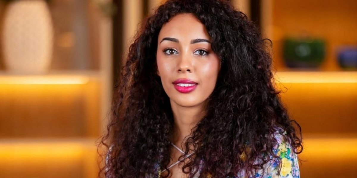 Une main humaine et une main robotique se touchant, symbolisant l'interaction entre l'humain et l'intelligence artificielle dans l'expérience client, avec un arrière-plan flou de la ville de Marrakech.