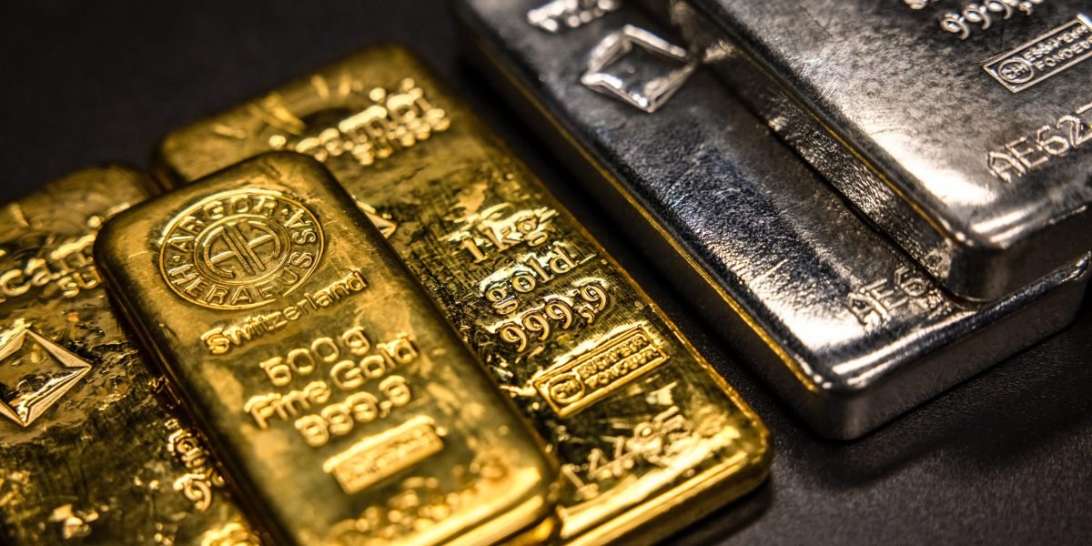 Gold and silver bars stacked next to a chart showing market volatility and price increases.