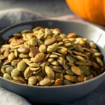 A handful of raw pumpkin seeds, also known as pepitas, ready to be eaten as a healthy snack.
