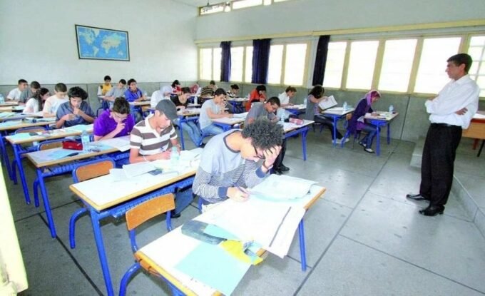 Des élèves marocains célébrant la qualification des Lions de l'Atlas pour la finale de la CAN 2025, avec des livres scolaires en arrière-plan.