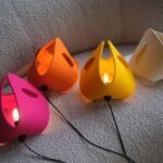 The SOFT lamp by TJ O'Keefe in a vibrant color, made from merino wool, resting on a sofa.