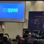 Vue d'une conférence sur la technologie avec des participants et des écrans affichant des graphiques liés au cloud et à l'IA.