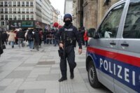 Un logo stylisé symbolisant la coopération internationale en matière de sécurité, avec les drapeaux de l'Autriche et du Maroc entrelacés, sur fond de carte du monde légèrement floue. Le tout est entouré d'un halo lumineux, évoquant la vigilance et le succès des opérations antiterroristes.