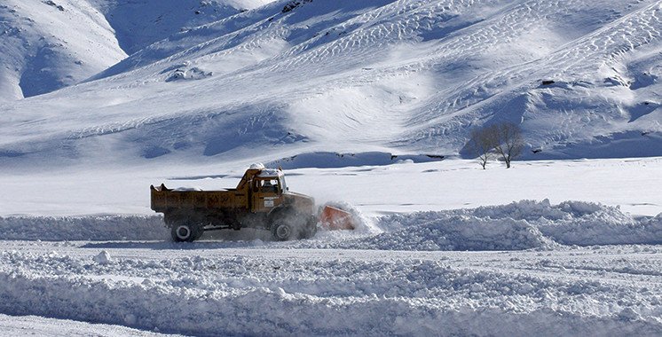 Vue aérienne d'une équipe de secours s'activant sur une pente enneigée du mont Toubkal, après une avalanche, avec des hélicoptères en arrière-plan.