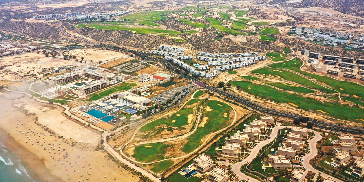 Vue aérienne de Taghazout Bay avec ses hôtels et ses plages, illustrant son dynamisme touristique.