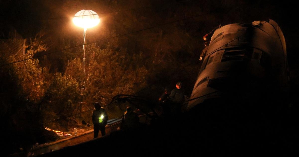 Vue nocturne des wagons déraillés après la collision de trains en Andalousie, entourés de secouristes et d'ambulances.