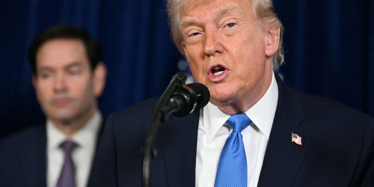 Donald Trump speaking at a press conference with a backdrop of the American flag, discussing Venezuela's oil economy.