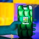 A person playing Wordle on a smartphone, with green, yellow, and grey letter tiles visible on the screen.