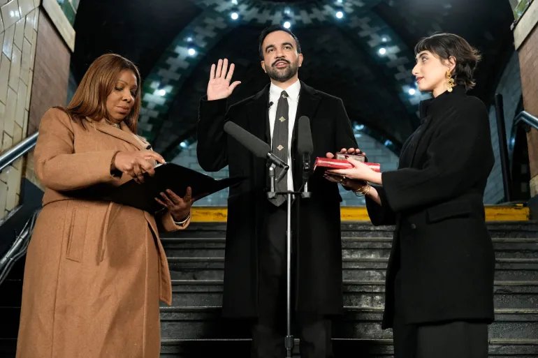 Zohran Mamdani taking his oath of office as New York City's mayor, hand on the Quran, at the historic City Hall subway station.