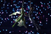 A vibrant image of the Verona Arena, host of the 2026 Winter Olympics Closing Ceremony, with a snowy mountain backdrop.