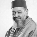 Portrait en noir et blanc d'Abdelhadi Belkhayat, le grand artiste marocain, souriant et élégant, micro à la main.