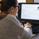 An abstract image depicting artificial intelligence influencing a job interview process, perhaps with a robot hand shaking a human hand, or AI symbols integrated into a resume.