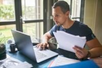 A person looking at a laptop screen displaying tax forms with AI interface elements, symbolizing the intersection of technology and finance.