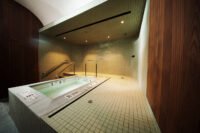 Interior view of Akari Greenpoint sauna, showcasing minimalist design, light green tiles, and a tranquil atmosphere.