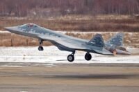 Un avion de chasse furtif Sukhoi Su-57 avec un camouflage 'Belaya Akula' (requin blanc) survolant un paysage désertique, symbolisant la présence potentielle en Algérie et les implications géopolitiques.