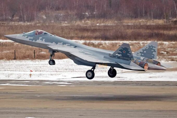 Un avion de chasse furtif Sukhoi Su-57 avec un camouflage 'Belaya Akula' (requin blanc) survolant un paysage désertique, symbolisant la présence potentielle en Algérie et les implications géopolitiques.