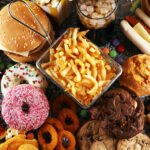 Assiette colorée avec des aliments frais et non transformés, contrastant avec des emballages d'aliments ultra-transformés en arrière-plan, symbolisant le débat sur la nutrition et la santé.