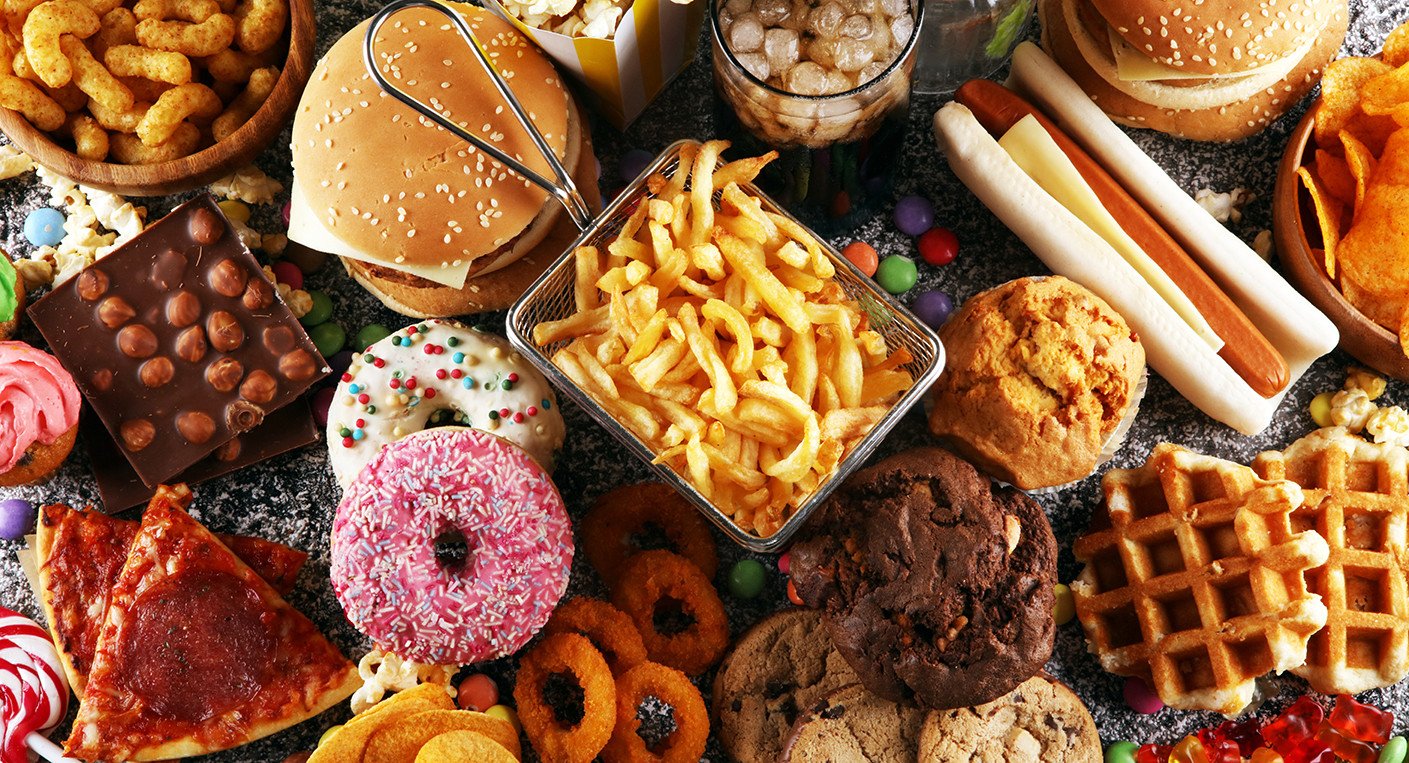 Assiette colorée avec des aliments frais et non transformés, contrastant avec des emballages d'aliments ultra-transformés en arrière-plan, symbolisant le débat sur la nutrition et la santé.