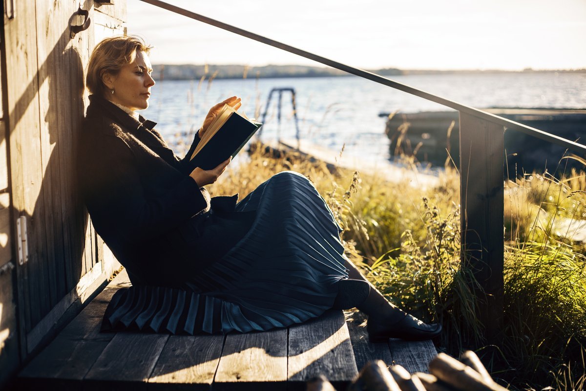 A person writing in a leather-bound journal with a vintage camera and a cup of coffee nearby, symbolizing a return to analog hobbies.