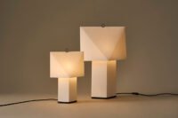 Aplat Table Lamp by CPRV for HAY, a folded paper lamp with a minimalist design, sitting on a table.